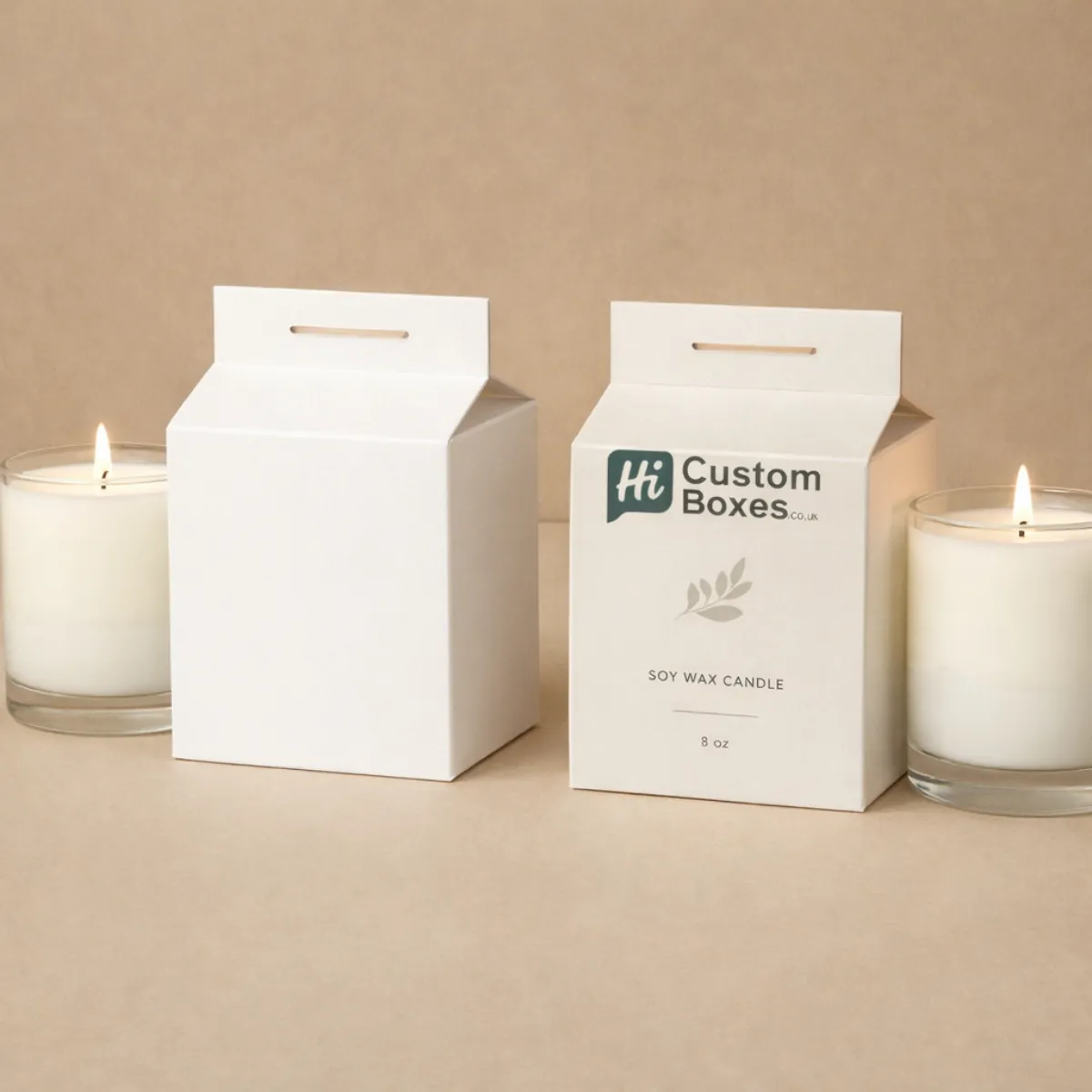 Two white gable-top milk carton style candle boxes with simple leaf motifs and glass candles. class=